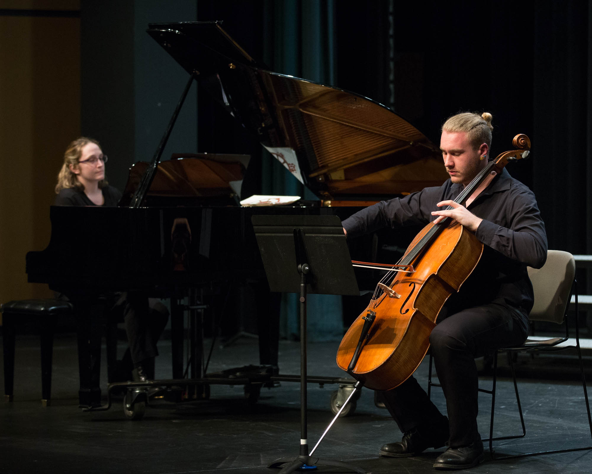 A Cellist playing to next to a piano