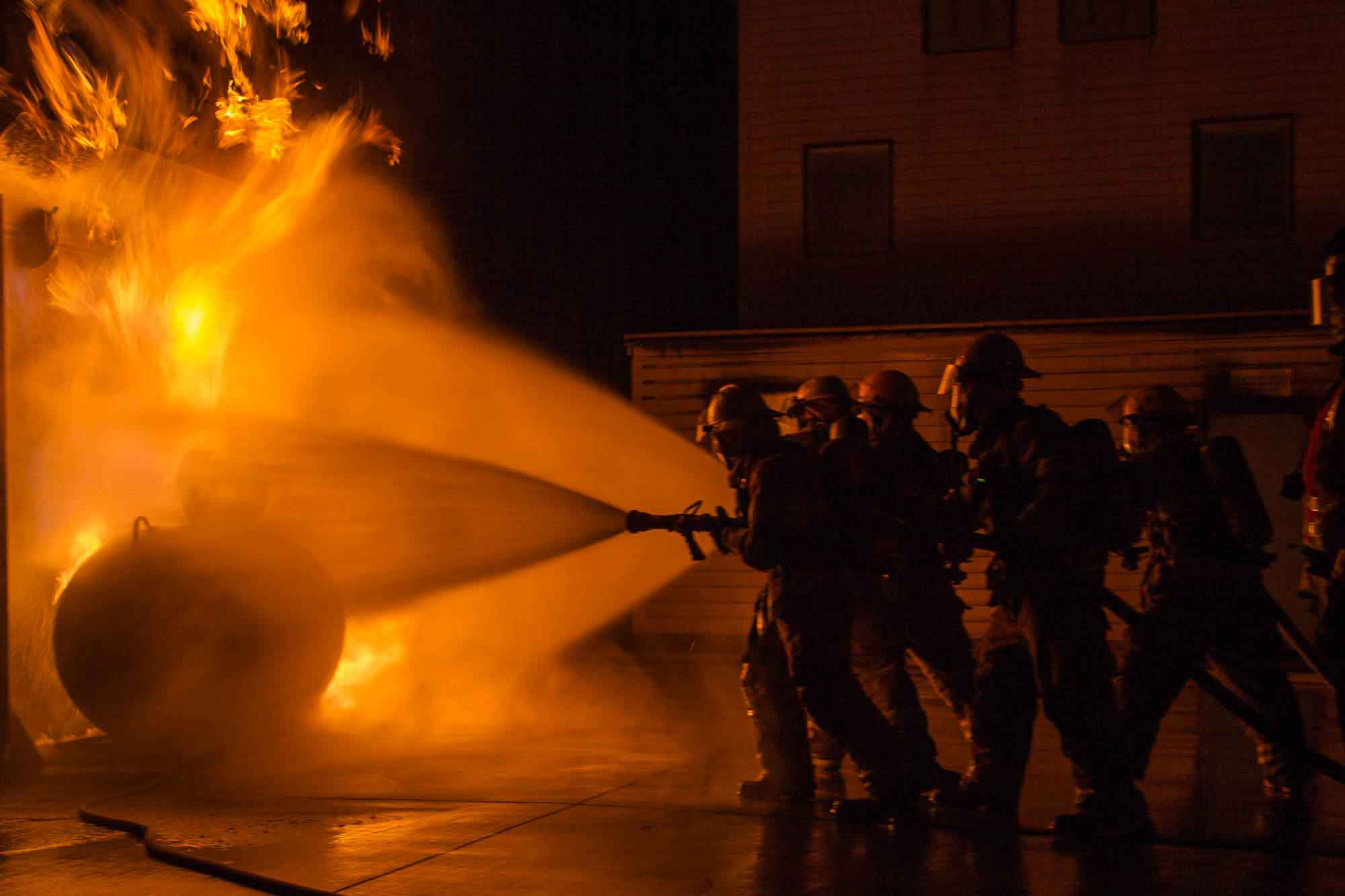 Four student firefighters practice putting out a fire