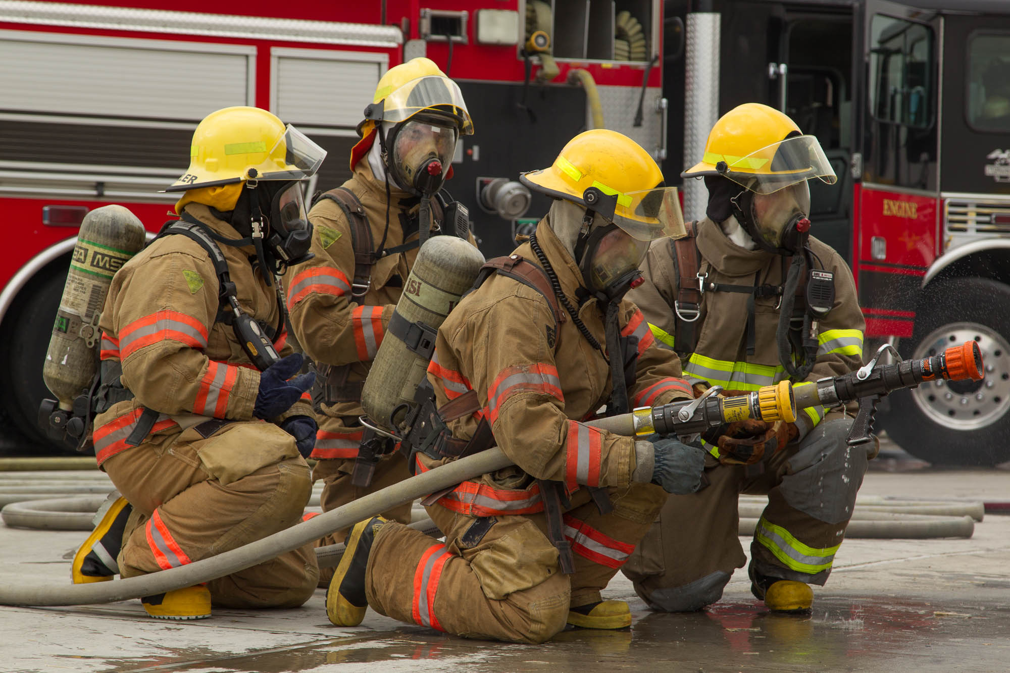 Firefighter hose crew spraying water on a fire