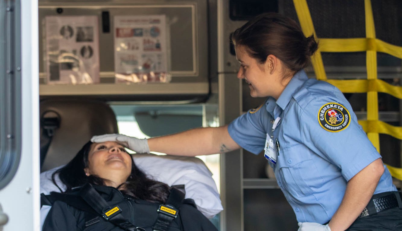 An EMS students treats a patient on a stretcher in the back of an ambulance during a practice drill.