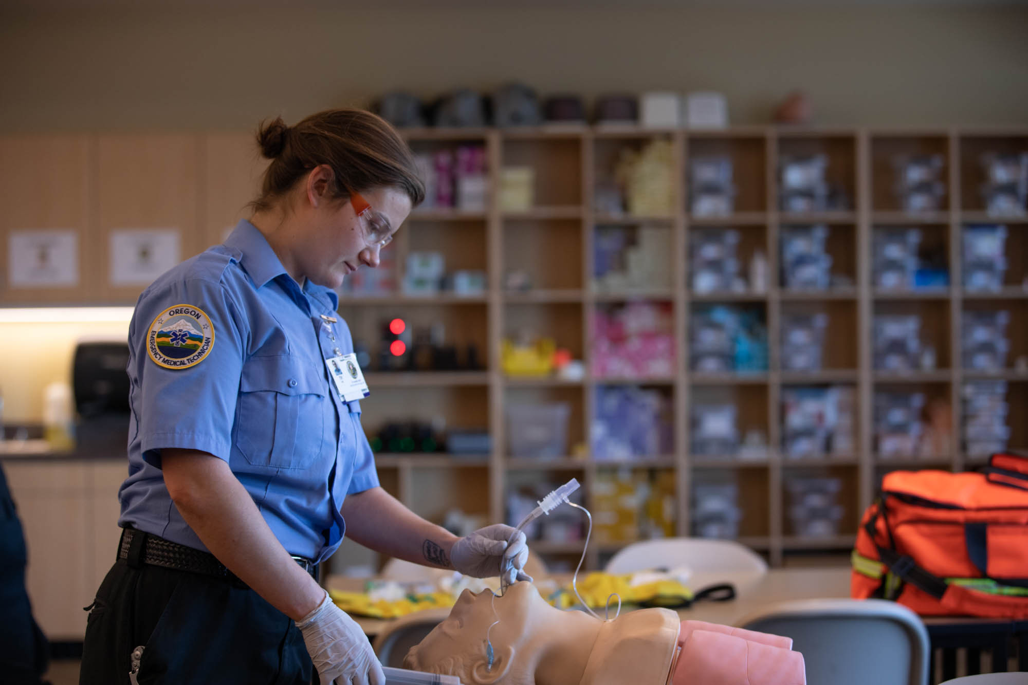 An EMT student practices on a training dummy in a lab.