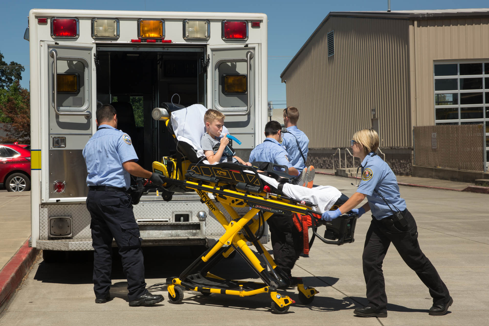 Students load a patient on a stretcher into the back of an ambulance during a practice drill.