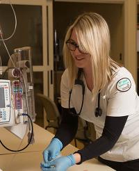A first-year nursing student administers an IV into the arm of a patient in a laboratory