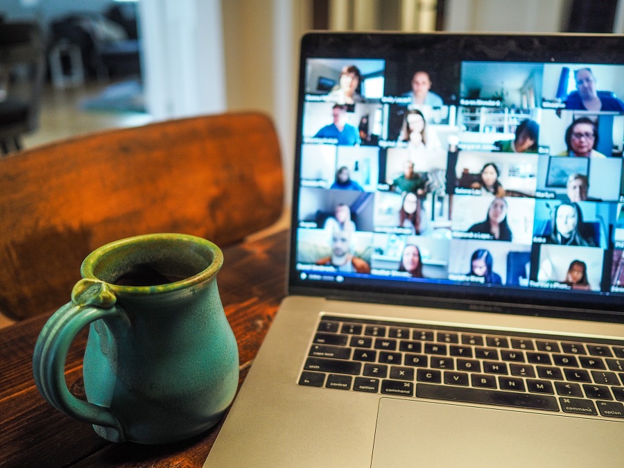 A coffee mug next to a laptop showing a virtual group meeting